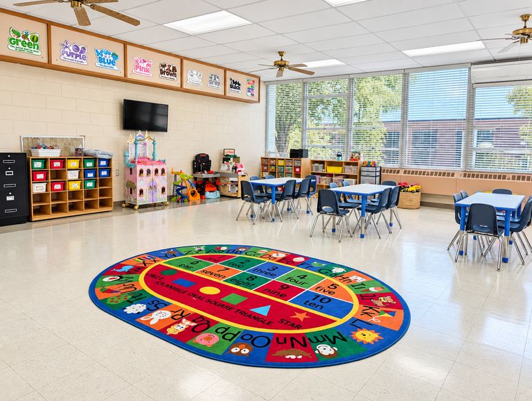 Classroom with a play kitchen, cubbies and a colorful rug