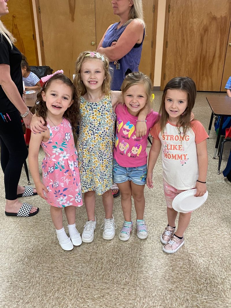 Four preschool girls standing together and smiling in the classroom