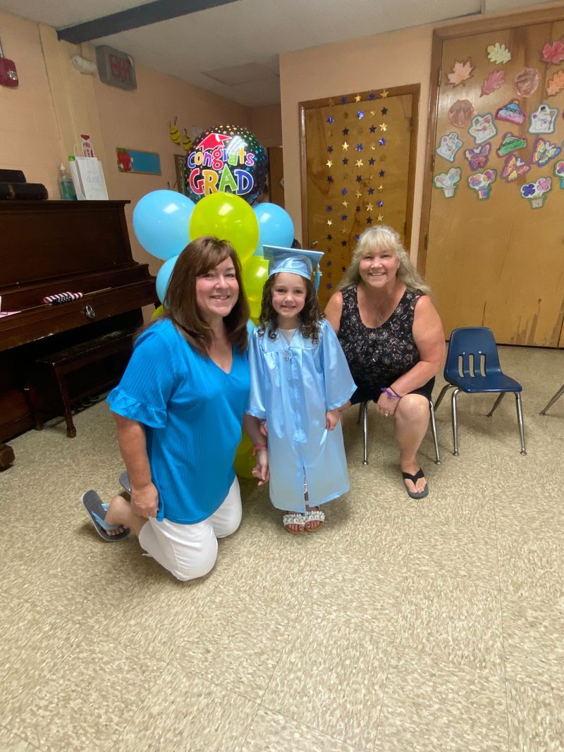 A graduate in a cap and gown celebrating with teachers and balloons