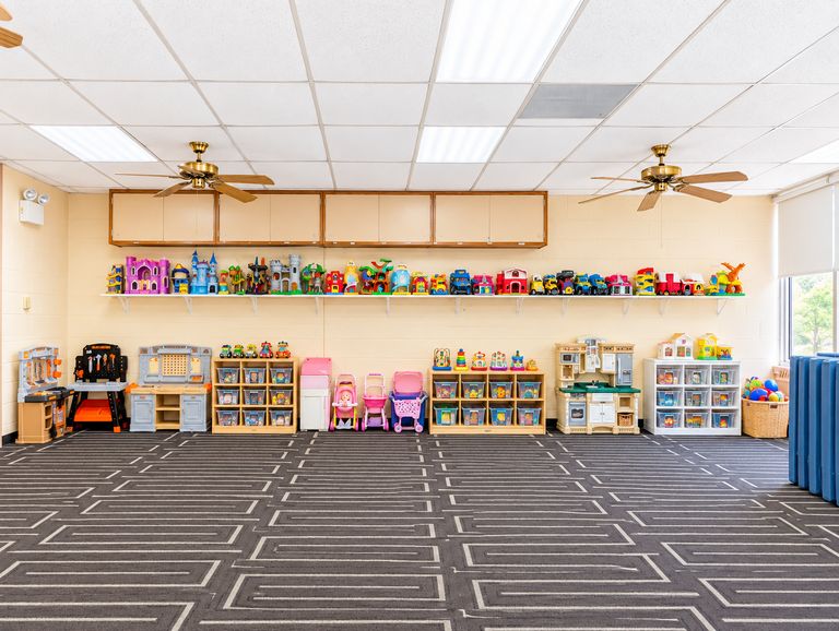 St. Luke's large indoor play room with toy shelves, a play kitchen and soft mats