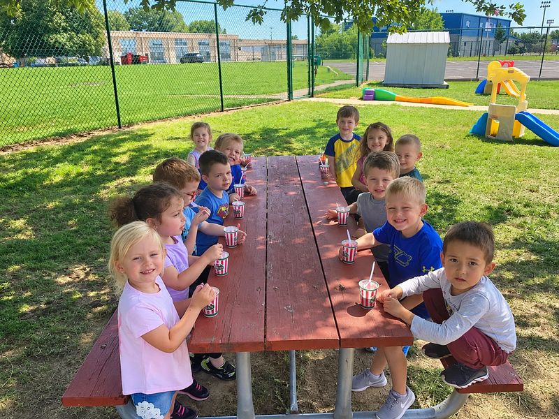Children enjoying a snack together at a picnic table on the St. Luke's playground