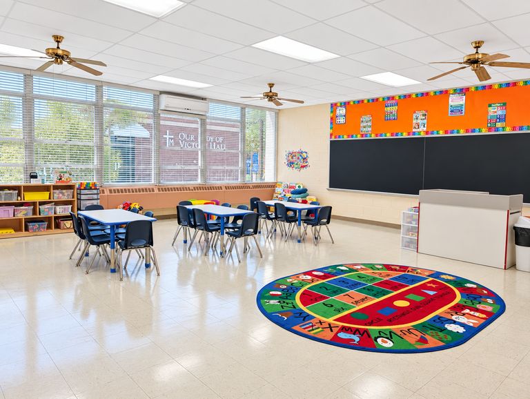 Pre-K classroom with tables, chairs and a colorful game rug