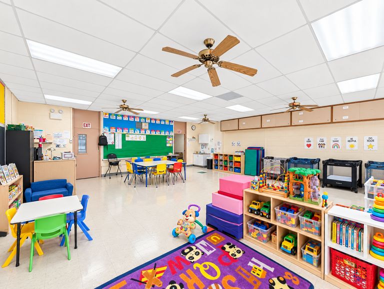 Toddler classroom with low tables, toy shelves and an alphabet rug